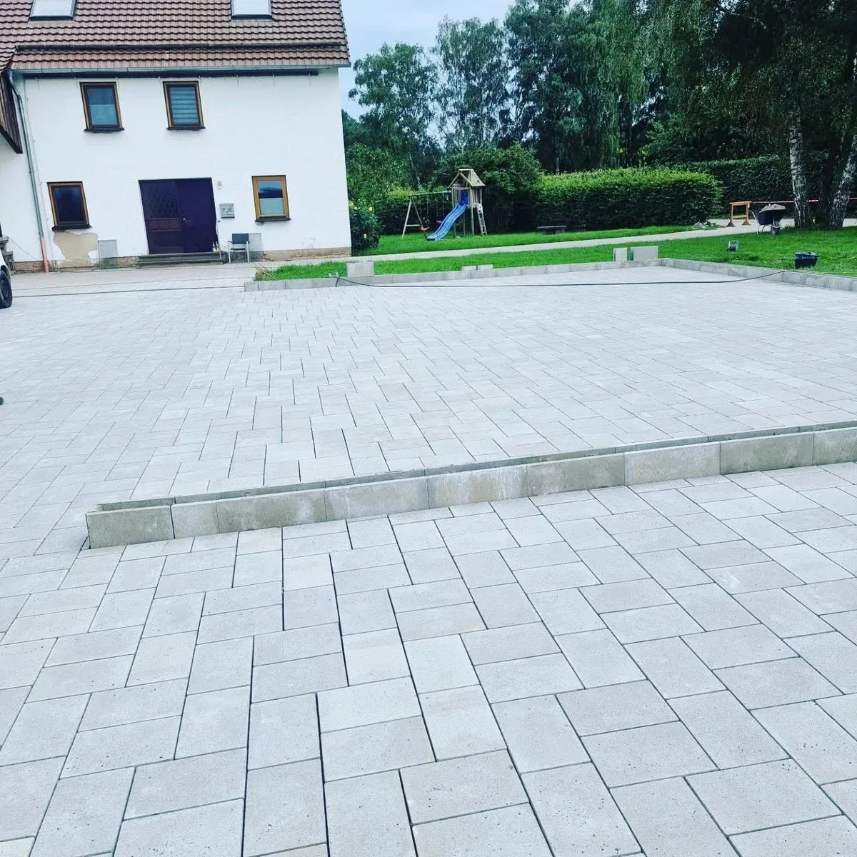Pflasterarbeiten: Hoffläche aus Betonpflaster mit einer niedrigen Stufe